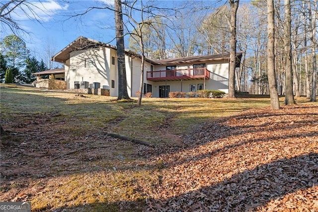 back of property featuring a yard, a wooden deck, and stucco siding