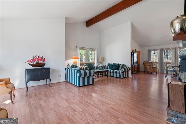 living area with high vaulted ceiling, beam ceiling, light wood-style flooring, and baseboards