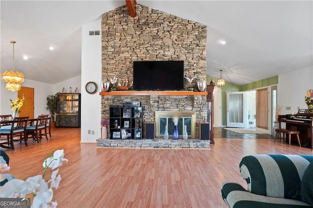 living area with vaulted ceiling with beams, a chandelier, a fireplace, and wood finished floors