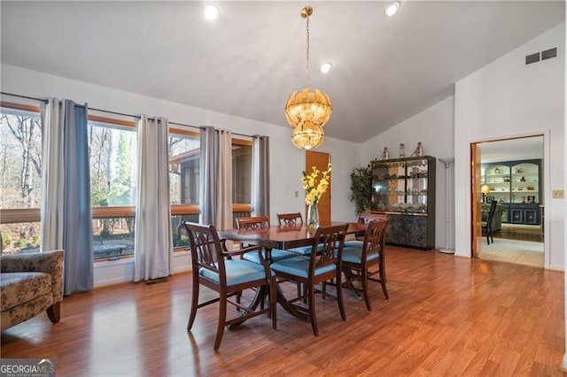 dining area featuring lofted ceiling, light wood-style flooring, visible vents, and a chandelier