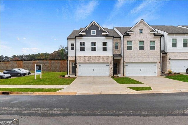 townhome / multi-family property with an attached garage, driveway, and a front yard