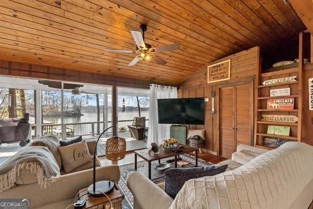 living area featuring wooden walls, a ceiling fan, wood ceiling, wood finished floors, and vaulted ceiling