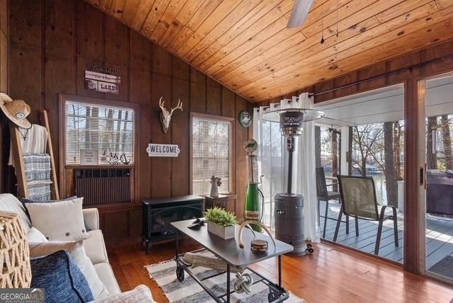 interior space with lofted ceiling, wood walls, wood finished floors, wood ceiling, and a wood stove