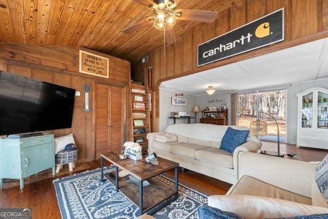 living room with wood ceiling, ceiling fan, wood walls, wood finished floors, and lofted ceiling