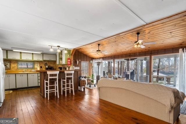 living area with wood-type flooring, a ceiling fan, and wood walls