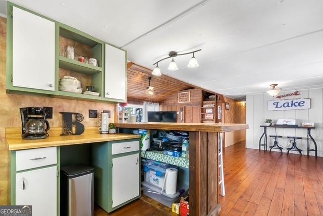 kitchen featuring lofted ceiling, light countertops, dark wood-style floors, open shelves, and green cabinetry