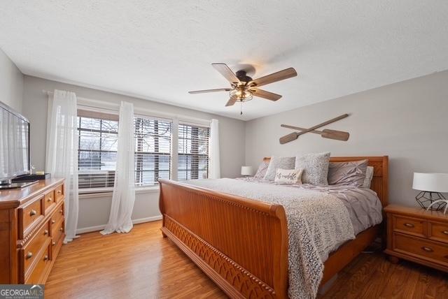 bedroom with ceiling fan, baseboards, and light wood-type flooring