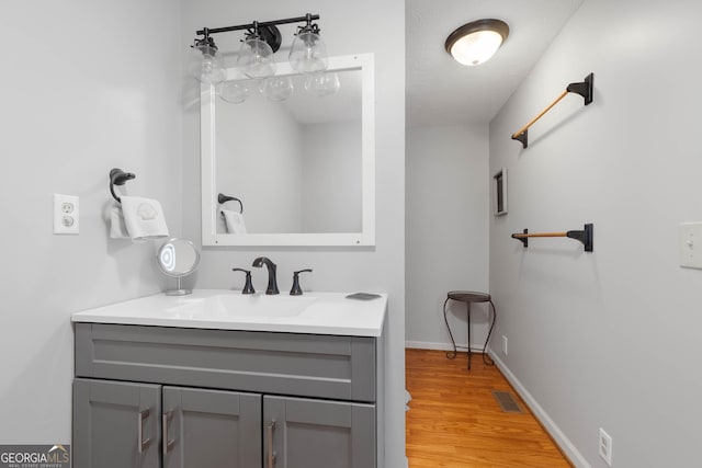 bathroom with visible vents, baseboards, wood finished floors, and vanity