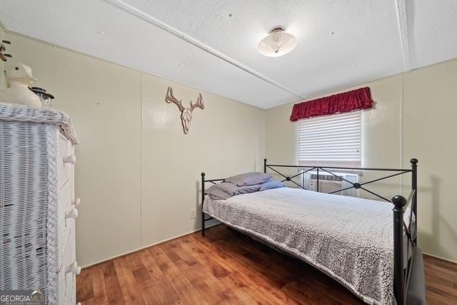 bedroom with a textured ceiling and wood finished floors