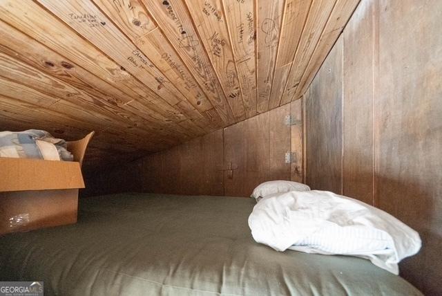 bedroom featuring carpet floors, wood walls, wooden ceiling, and vaulted ceiling