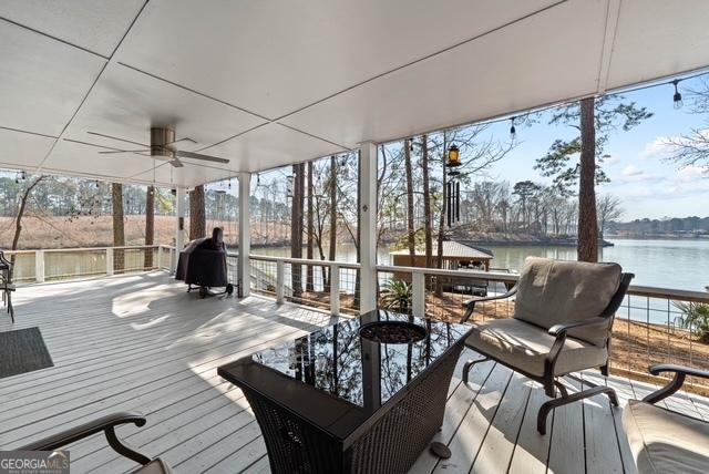 wooden deck with a water view, ceiling fan, and area for grilling
