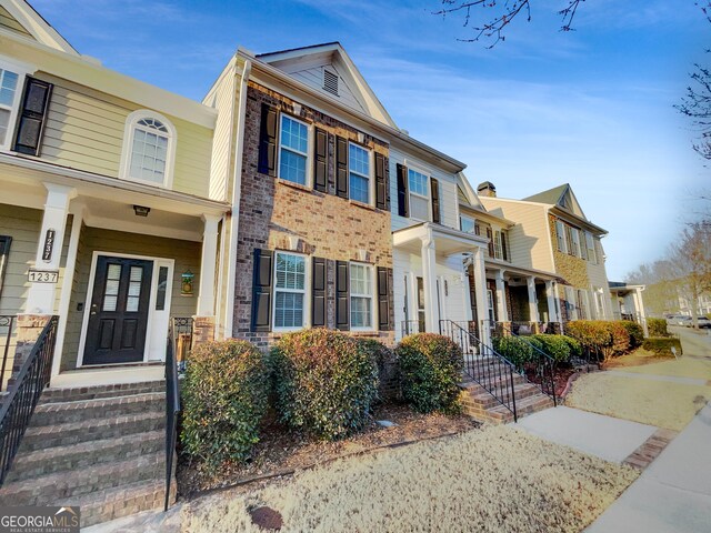 1235 Park Pass Way, Suwanee, GA 30024 - townhome / multi-family property with covered porch, a residential view, and brick siding
