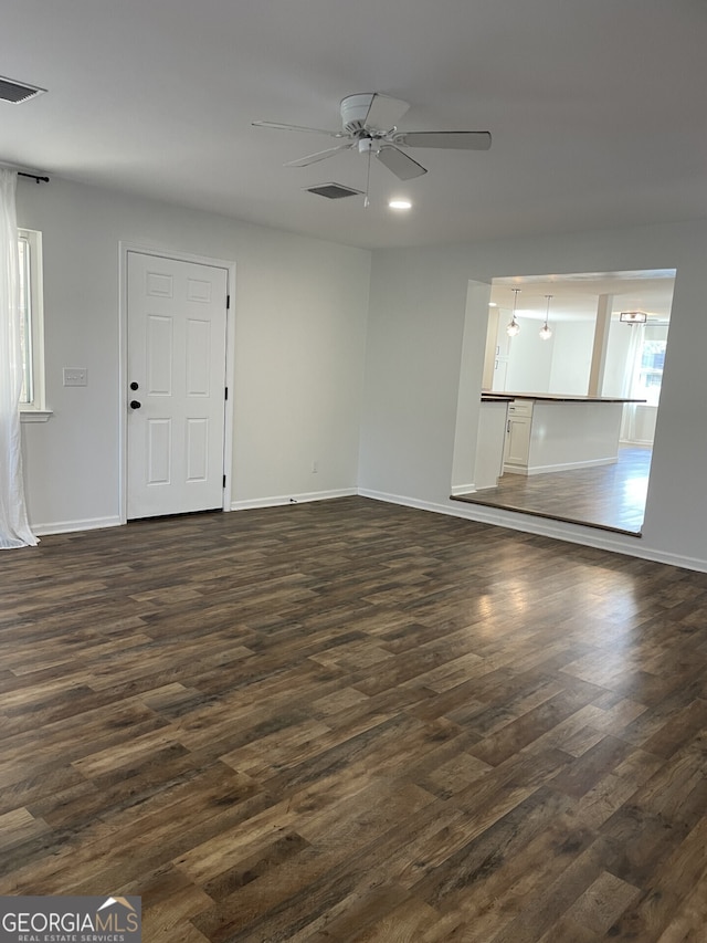 unfurnished living room featuring dark wood-type flooring, visible vents, and baseboards