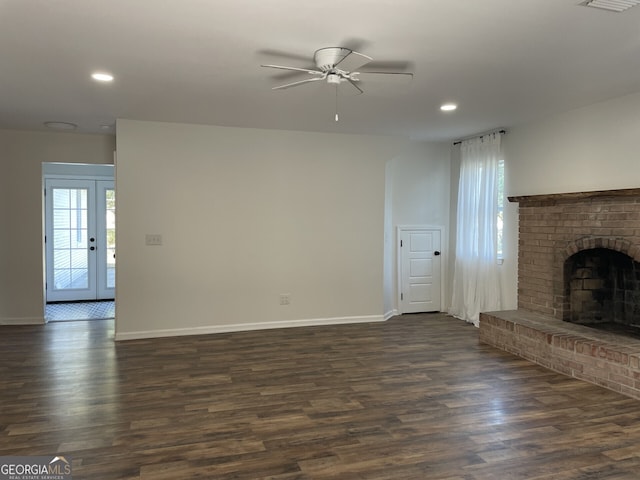 unfurnished living room featuring a fireplace, baseboards, and dark wood-type flooring