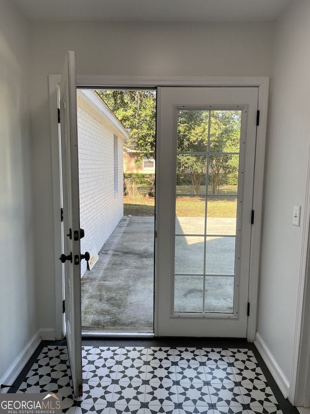 doorway to outside with baseboards and tile patterned floors