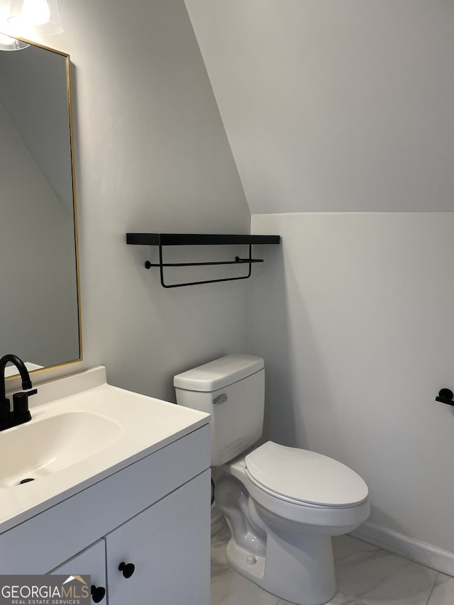 half bath with baseboards, toilet, lofted ceiling, marble finish floor, and vanity