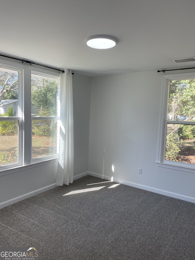 carpeted empty room featuring a wealth of natural light, visible vents, and baseboards