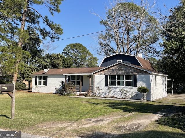 view of front facade featuring brick siding, a front yard, and a gambrel roof