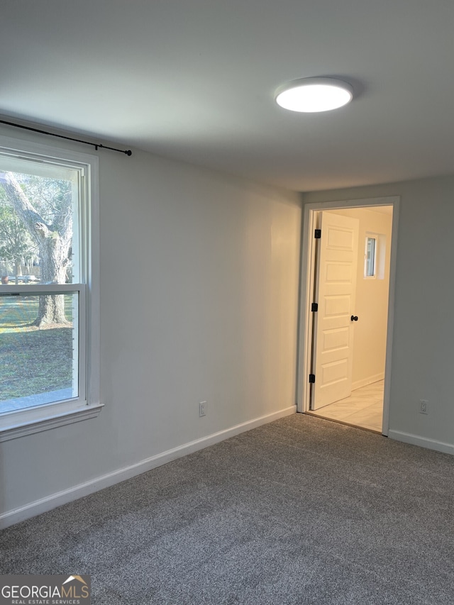 carpeted spare room featuring plenty of natural light and baseboards