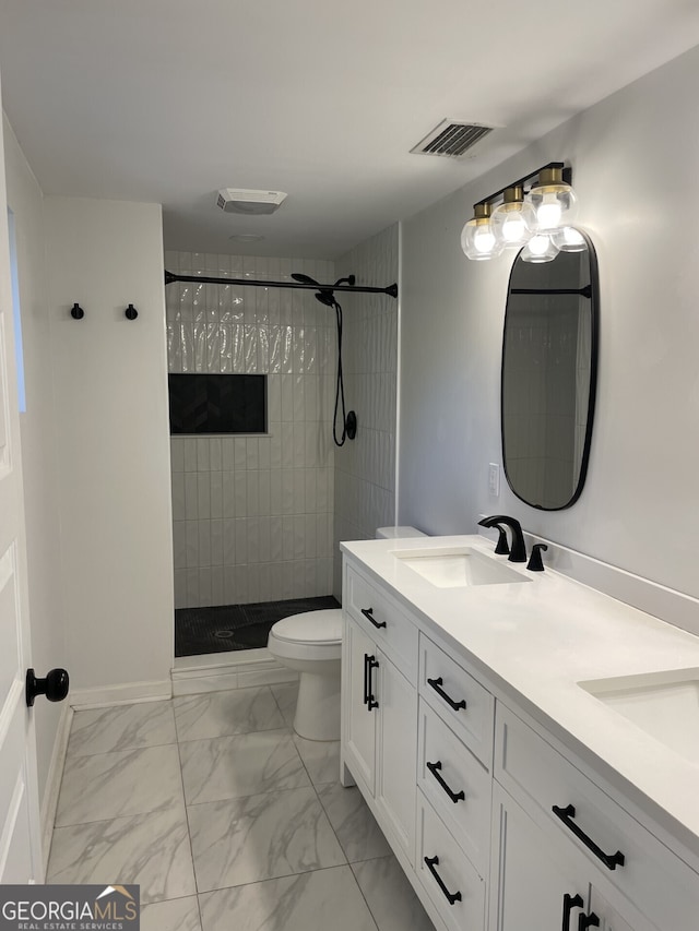 bathroom with marble finish floor, visible vents, a sink, and tiled shower