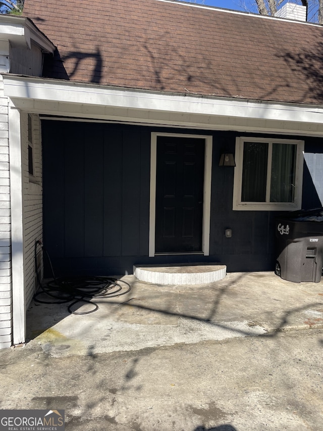 entrance to property featuring roof with shingles