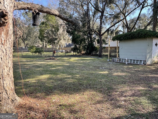 view of yard featuring an outbuilding, fence, and a storage unit