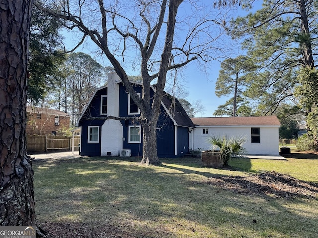 rear view of house with brick siding, fence, and a lawn