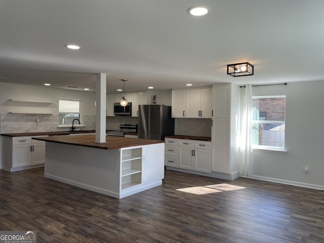 kitchen with white cabinets, butcher block countertops, appliances with stainless steel finishes, and open shelves