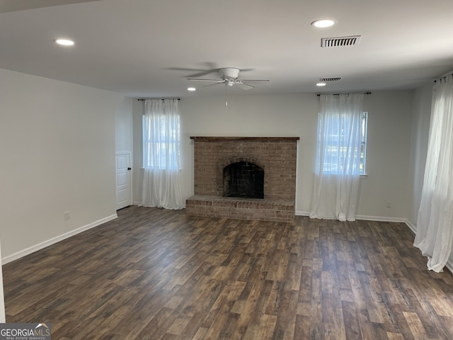 unfurnished living room with dark wood-type flooring, recessed lighting, a brick fireplace, and visible vents