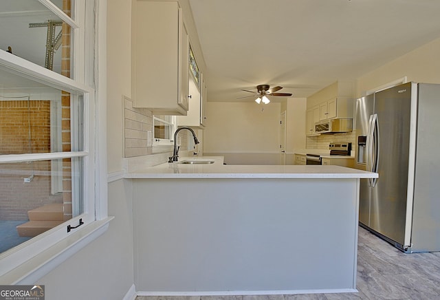 kitchen featuring tasteful backsplash, light countertops, appliances with stainless steel finishes, a ceiling fan, and a sink