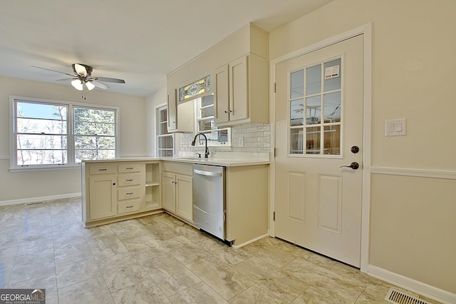 kitchen featuring tasteful backsplash, light countertops, visible vents, a sink, and dishwasher