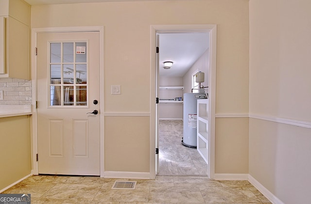 entryway with water heater, visible vents, and baseboards