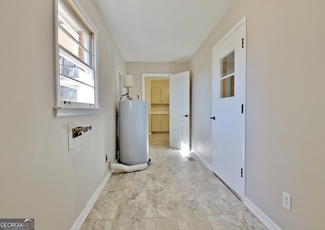 clothes washing area with laundry area, baseboards, washer hookup, and gas water heater