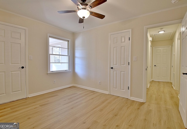 unfurnished bedroom with light wood-style floors, attic access, baseboards, and crown molding