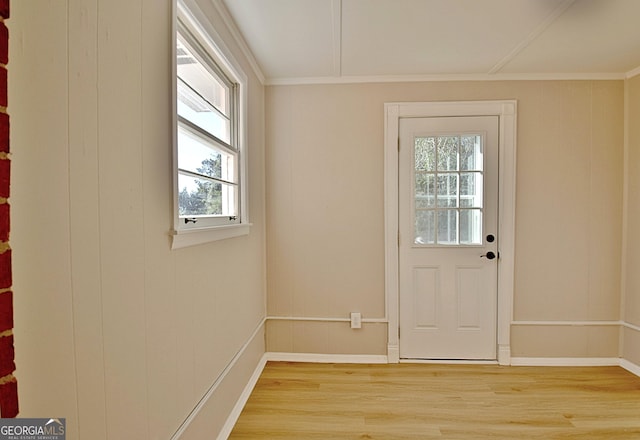 doorway to outside featuring ornamental molding, light wood-type flooring, and baseboards