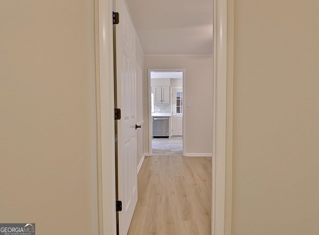 hall with ornamental molding and light wood finished floors