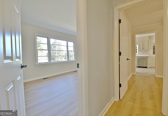 hallway featuring light wood-style floors, visible vents, and baseboards