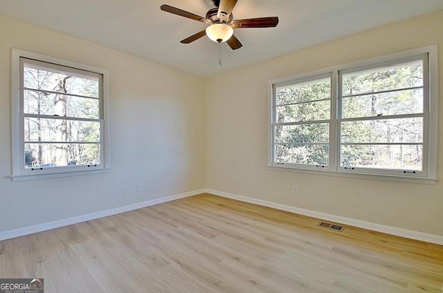 spare room featuring ceiling fan, light wood finished floors, visible vents, and baseboards