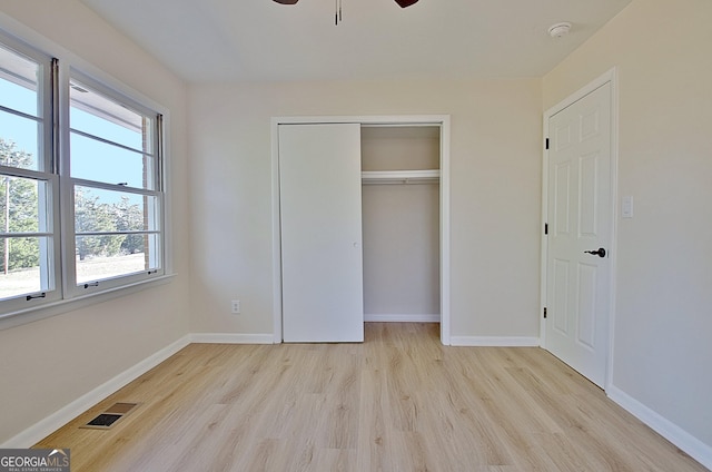 unfurnished bedroom featuring a closet, visible vents, baseboards, and wood finished floors