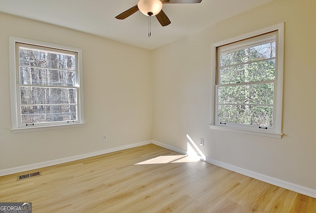 empty room featuring a ceiling fan, baseboards, visible vents, and wood finished floors