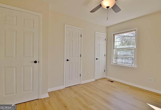 unfurnished bedroom with a ceiling fan, wood finished floors, visible vents, and baseboards