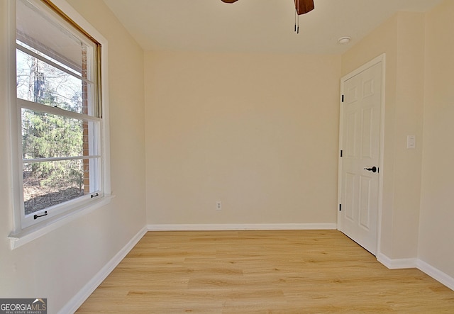 empty room with baseboards, ceiling fan, and light wood-style floors