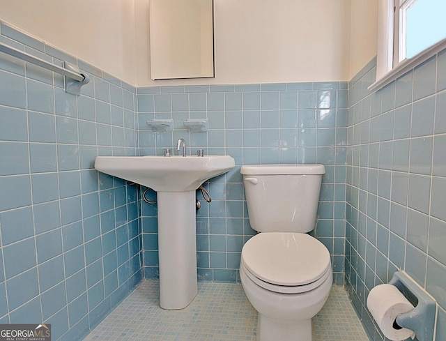 bathroom with toilet, a wainscoted wall, tile walls, and tile patterned floors