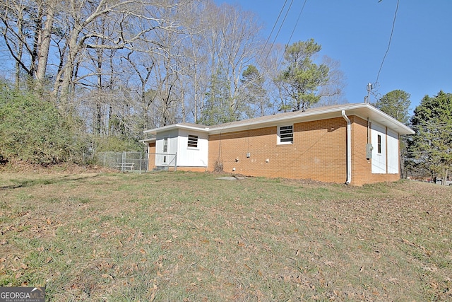 back of house featuring brick siding and a yard