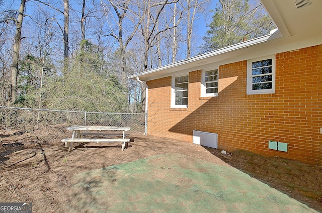 view of side of home with brick siding, crawl space, and fence