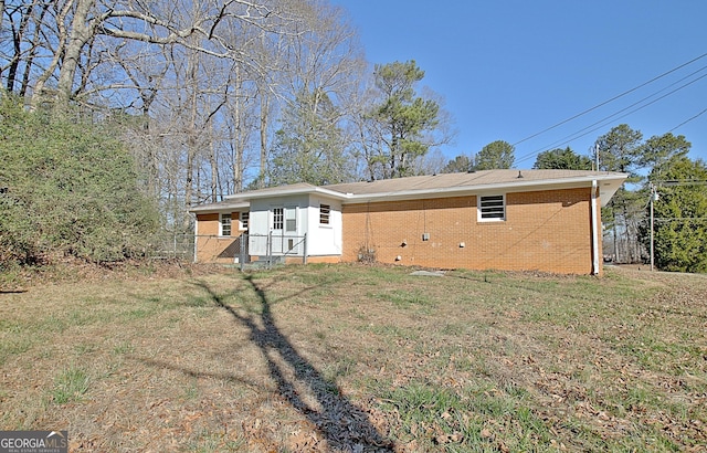 rear view of house featuring brick siding and a yard