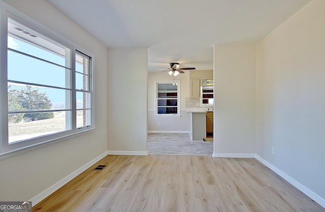 spare room with light wood finished floors, baseboards, visible vents, and ceiling fan