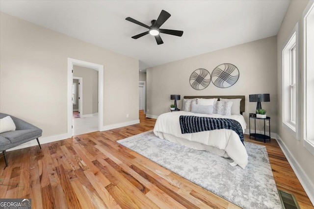 bedroom featuring a ceiling fan, baseboards, visible vents, and wood finished floors