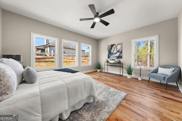 bedroom with multiple windows, ceiling fan, light wood-style flooring, and baseboards