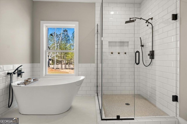 full bathroom featuring a stall shower, wainscoting, tile walls, and a soaking tub